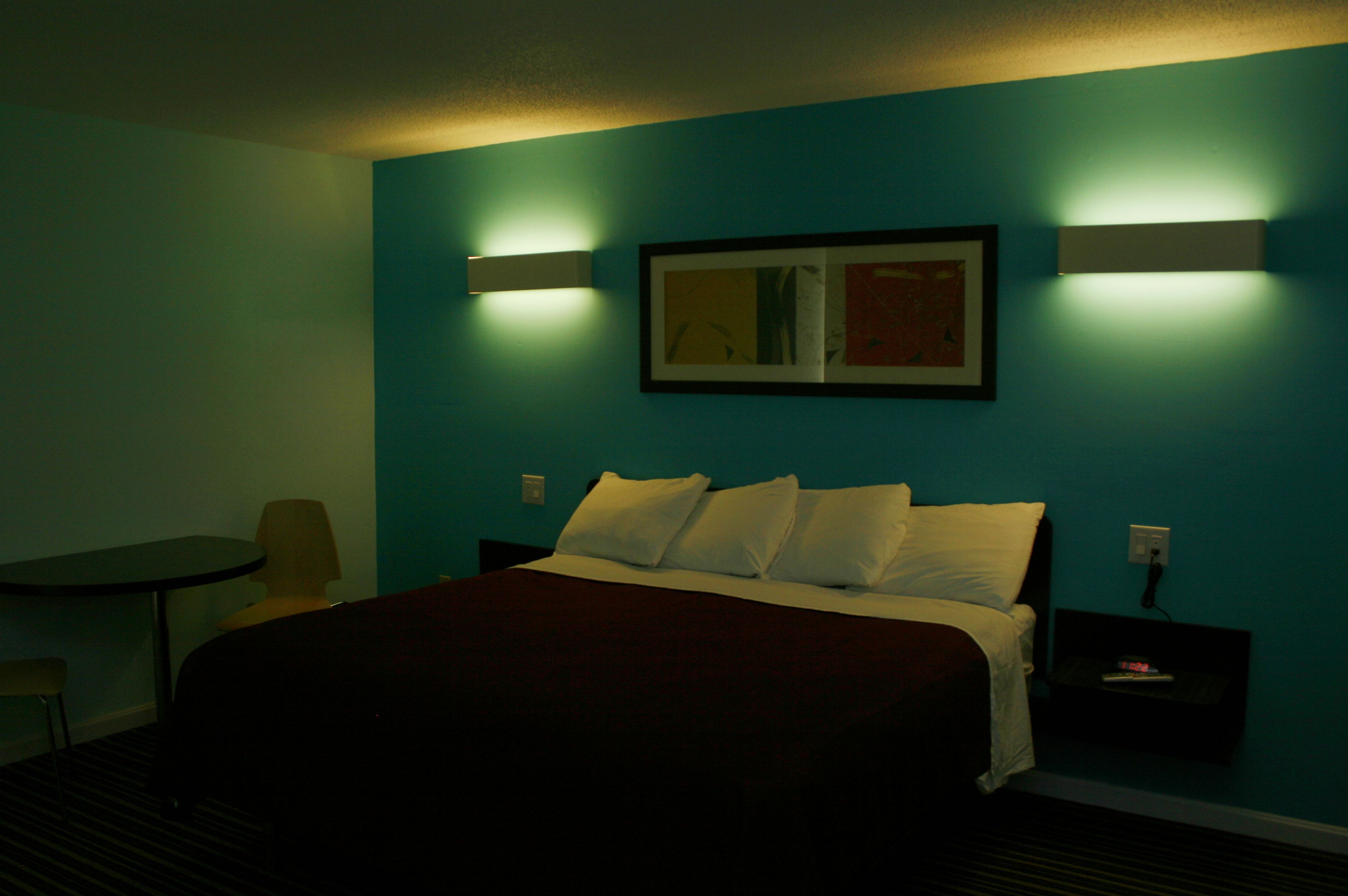 Una habitación de hotel con una cama, una mesita de noche, una silla y una mesa.