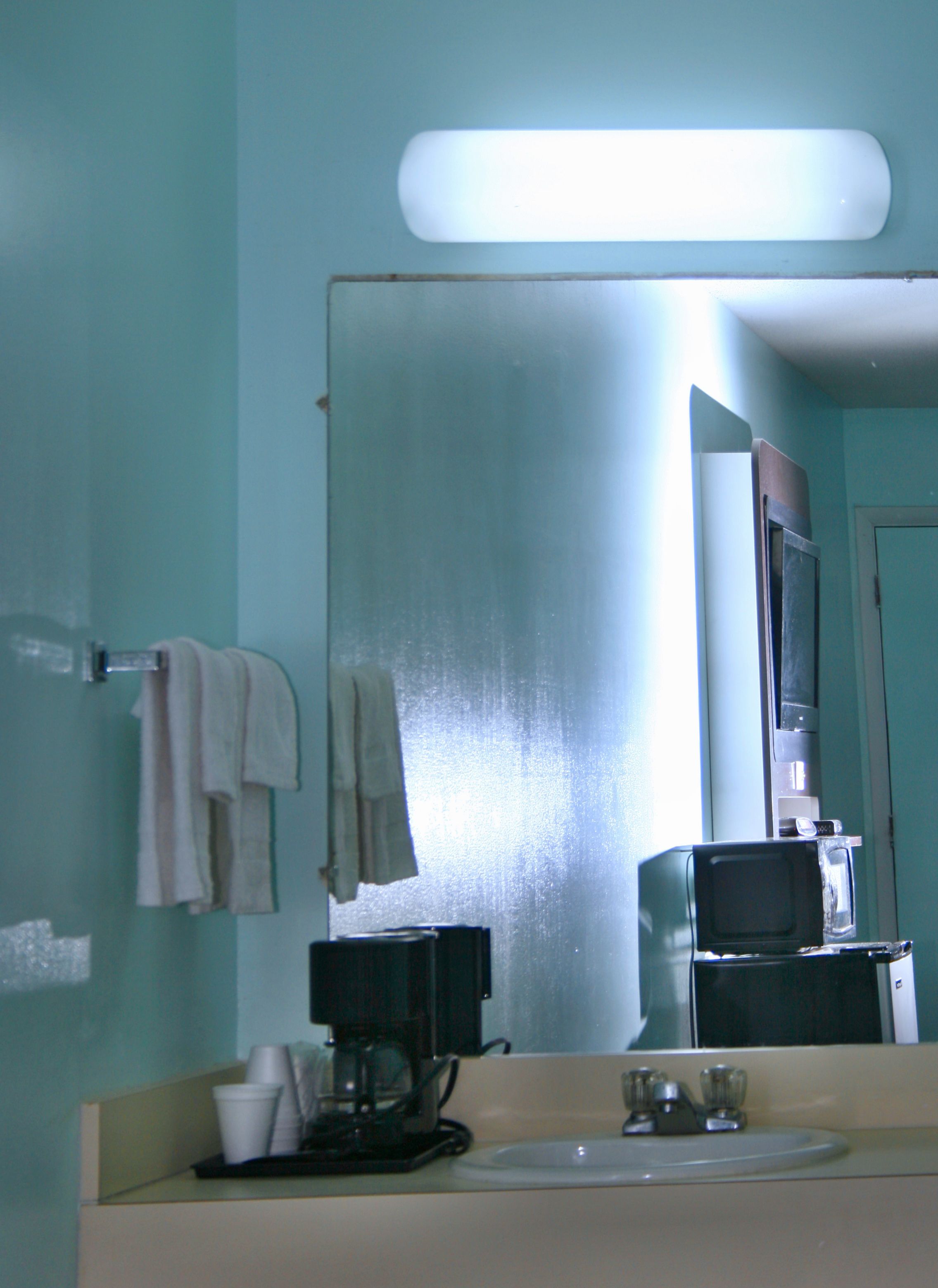 Une salle de bain équipée d’un lavabo, d’un miroir et d’une machine à café.