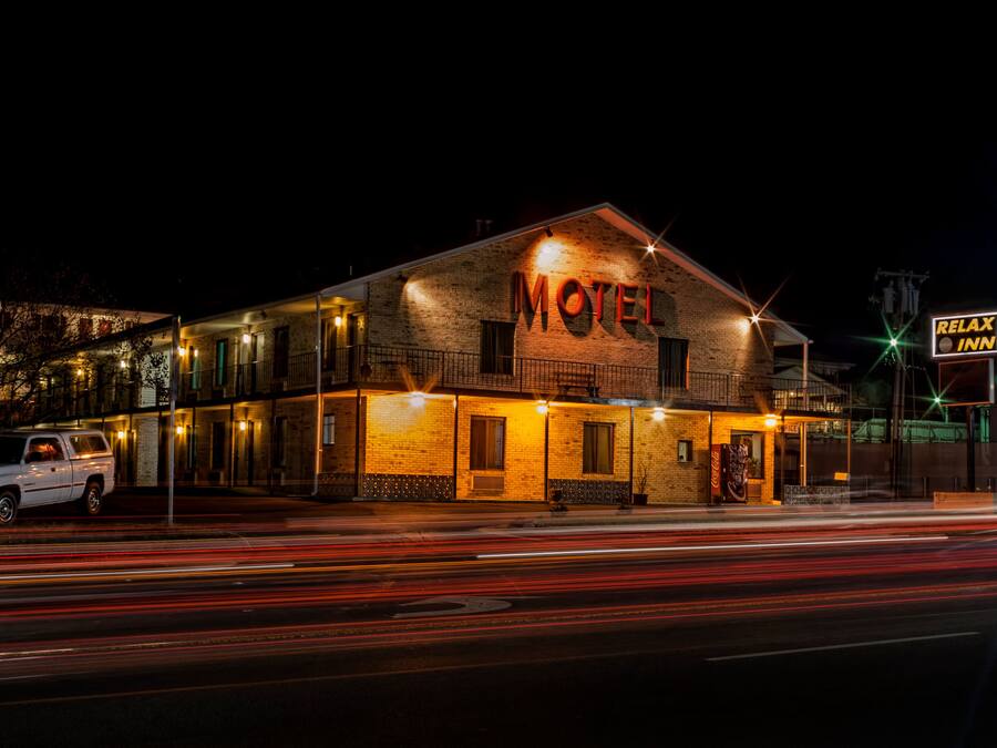 A brick building with a sign reading "Motel" and a neon sign for "Relax Inn" on the right.