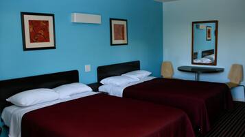 Una habitación de hotel con dos camas individuales, una mesita redonda pequeña, dos sillas y dos cuadros enmarcados en las paredes.