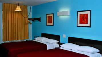 A room with two beds, a hanging light, and two framed pictures on the wall.