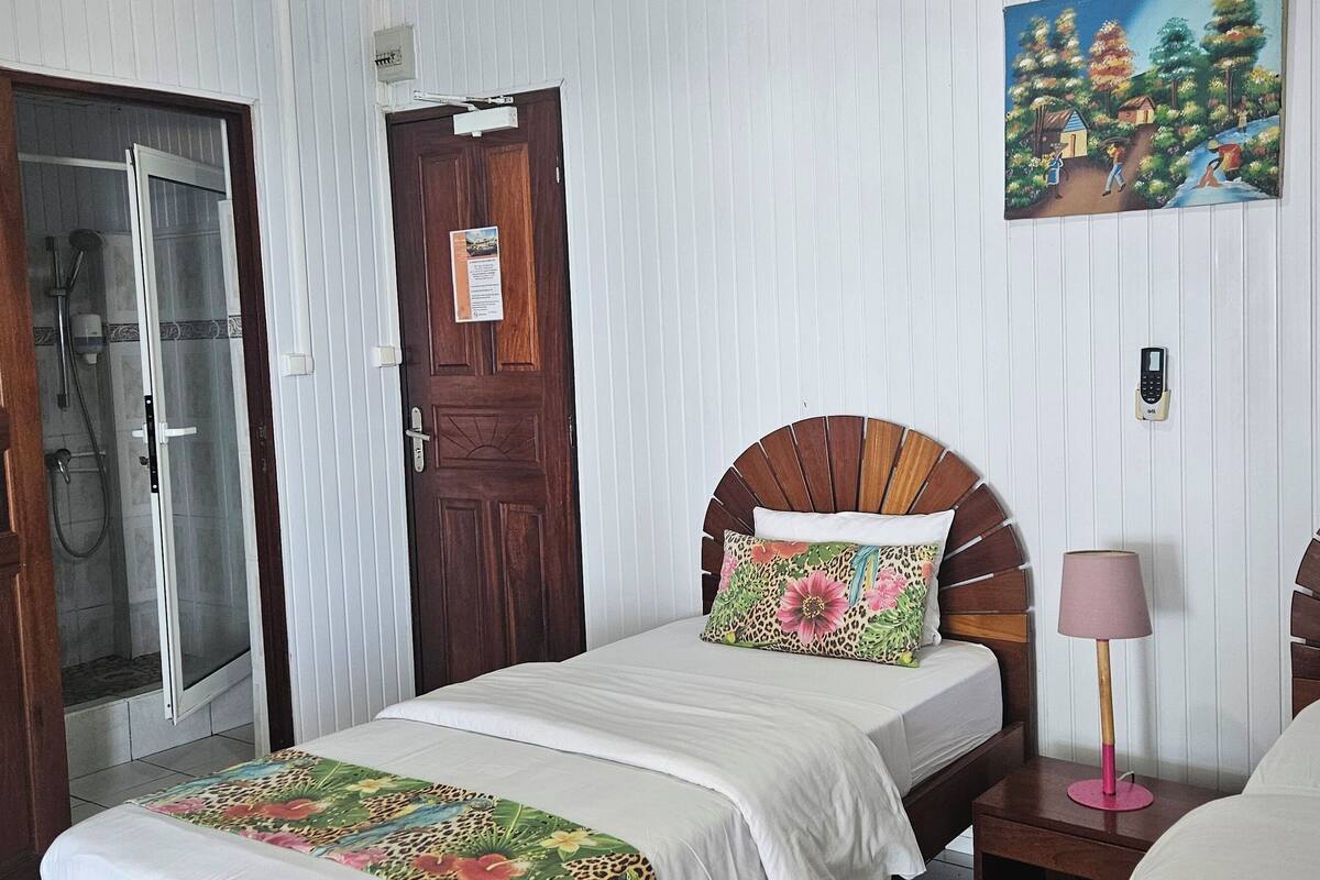 A hotel room with two beds, a shower, and a painting on the wall.