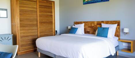 Un dormitorio con una cama grande, cabecera de madera y un cuadro de veleros en la pared.