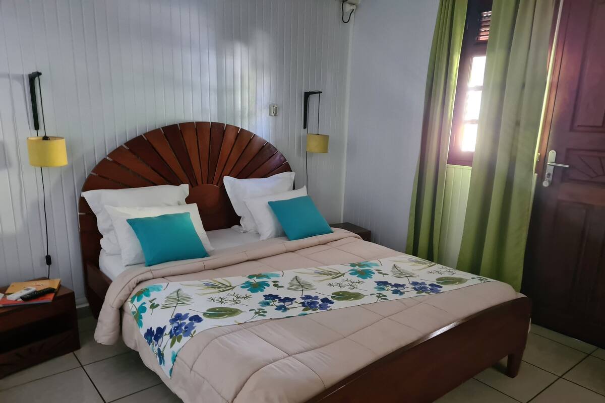A neatly made bed with a floral duvet, two bedside tables with lamps, and a wooden headboard.