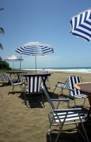 En la playa, sillas reclinables de playa, sombrillas, toallas de playa