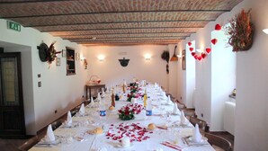 Ein langer Esstisch, festlich gedeckt für eine formelle Veranstaltung, mit weißen Tischdecken, Gläsern und floralen Tischarrangements.