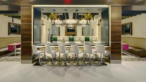 A modern dining area with a central bar, multiple chairs, and pendant lighting. - The Brooklyn (Brooklyn)
