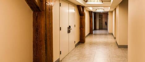 Un pasillo de hotel con vigas de madera, paredes color beige y piso de baldosas.
