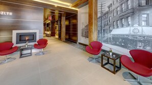 A modern lobby with a fireplace, red chairs, and a large wall mural of a historic building. - The Brooklyn (Brooklyn)