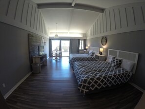 A hotel room with two beds, a TV, a dining table, and a view of the outdoors. - Ridgemark Golf Club & Resort (Hollister)
