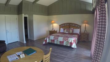 A bedroom with a large bed, two bedside lamps, a wooden headboard, and a checkered curtain.