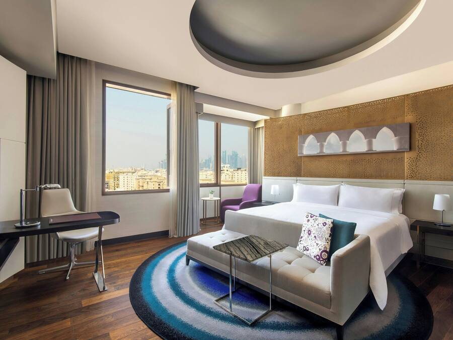 Un hotel moderno con una cama grande, un escritorio, una silla y vistas a la ciudad.