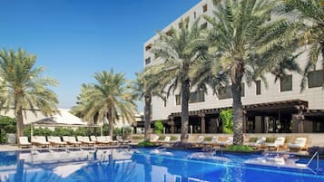 Una piscina techada, una piscina al aire libre, sombrillas