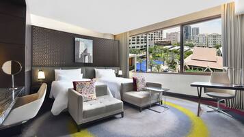 Un hotel moderno con cama, dos sofás, una mesita y vistas a la ciudad.