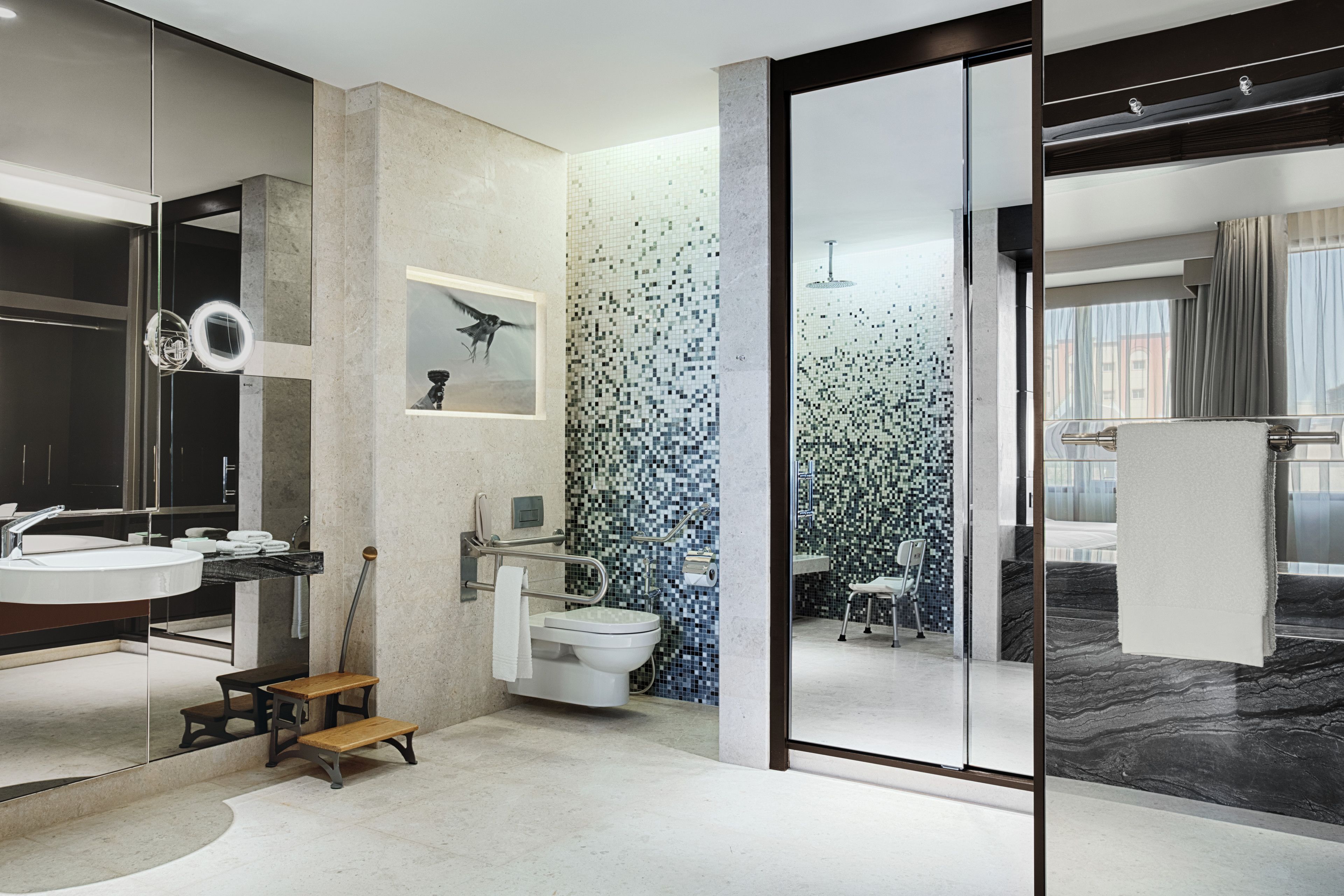 A modern bathroom with a large mirror, a toilet, and a sink.
