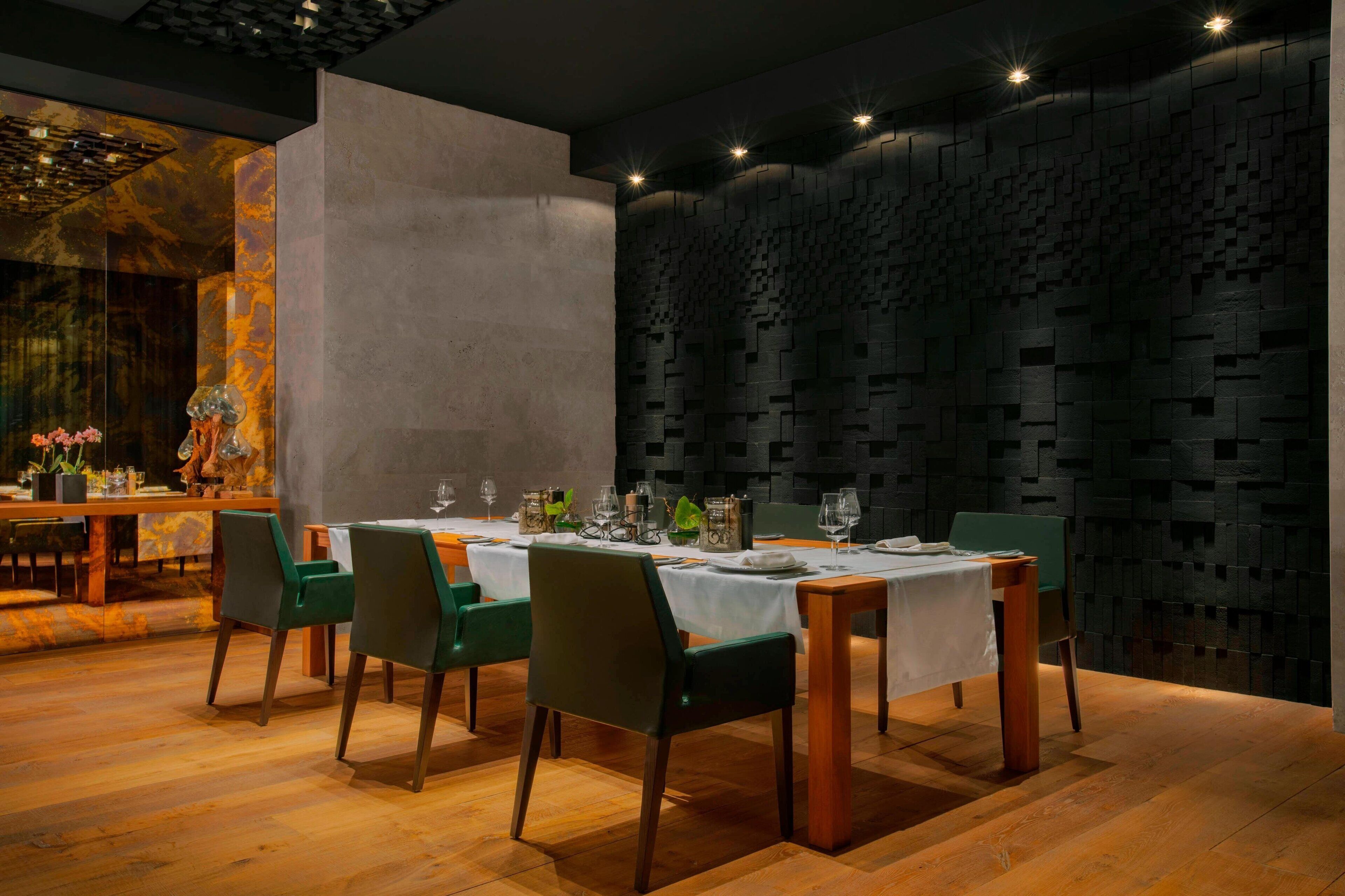 Comedor con una mesa larga dispuesta para seis personas, rodeada de sillas verdes.
