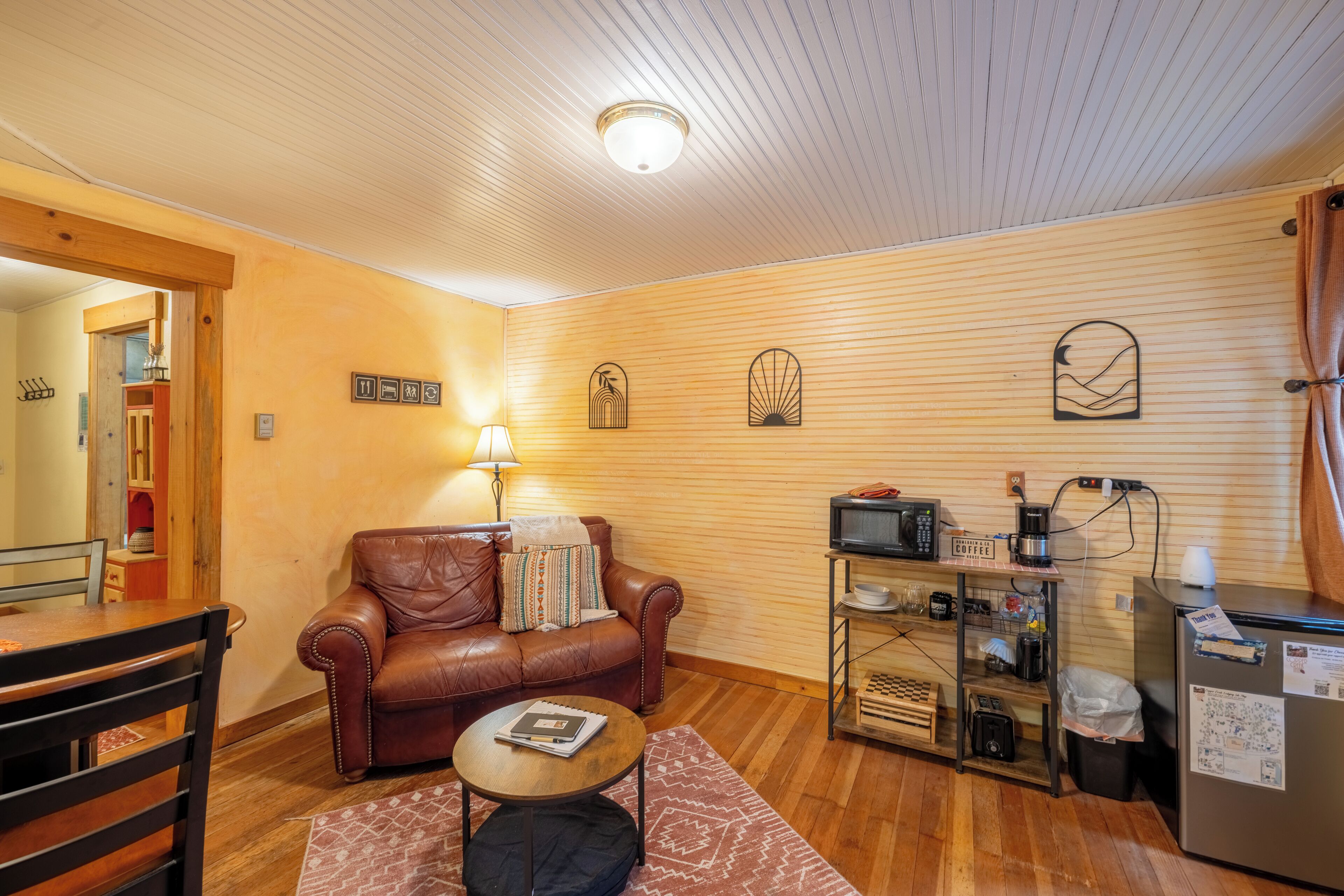 A cozy living room with a leather sofa, a coffee table, and a wooden coffee station.