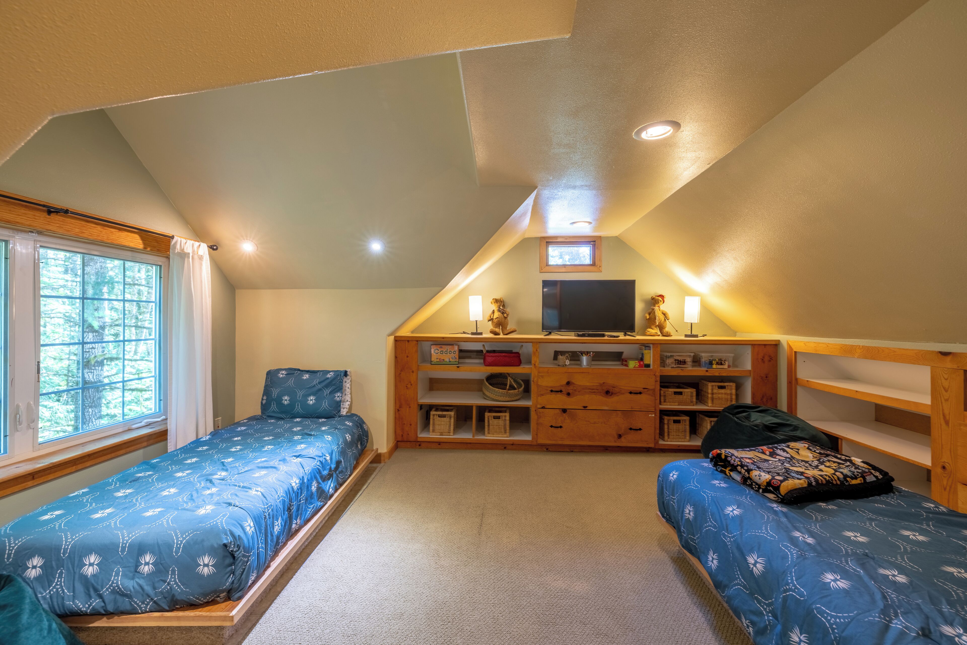 Un dormitorio con dos camas individuales, un aparador de madera, un televisor y un tragaluz.