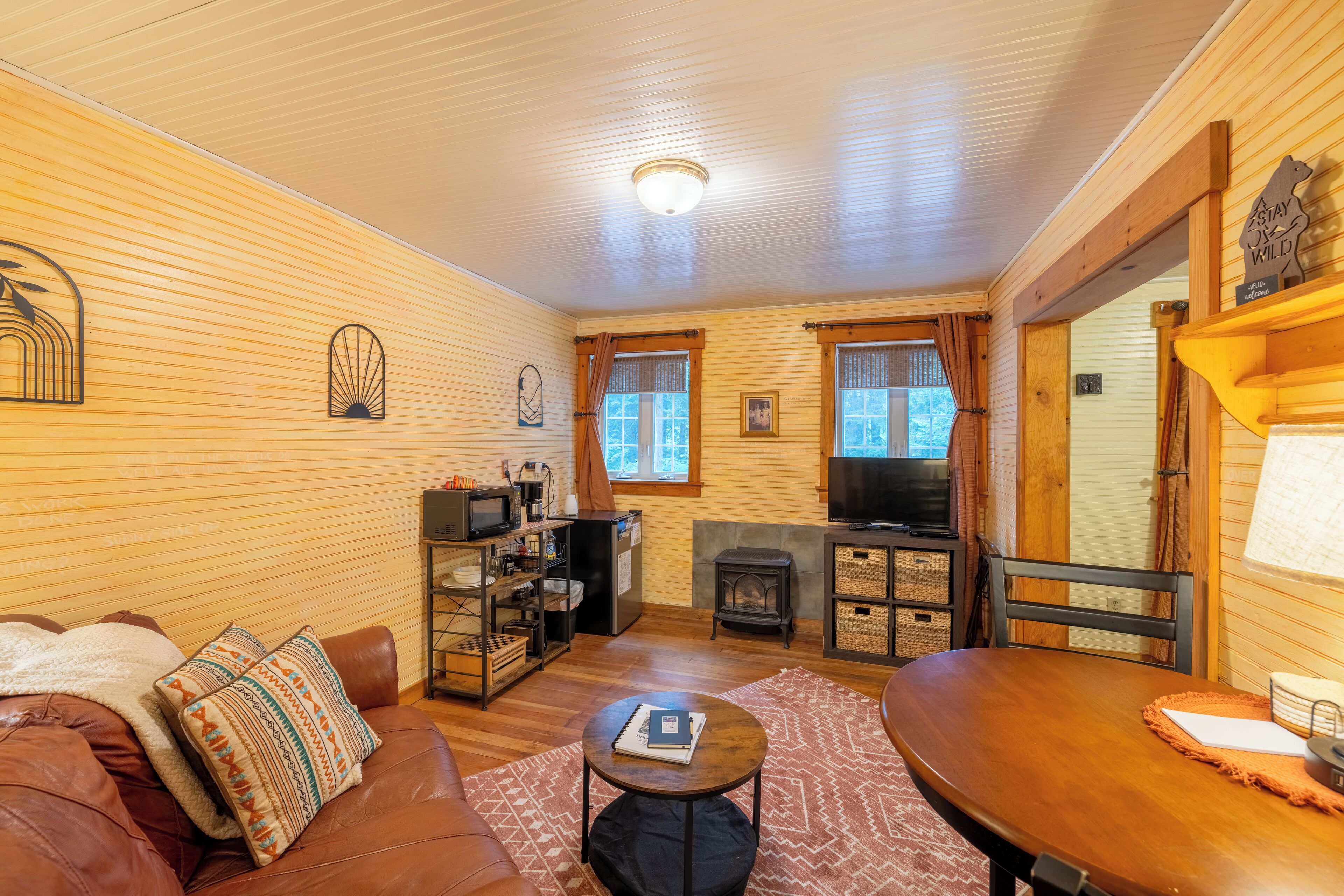 A cozy living room with a brown leather sofa, a wooden dining table, and a fireplace.