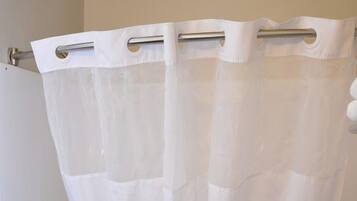 A bathroom with a white bathtub, a shower curtain, and a towel rack.