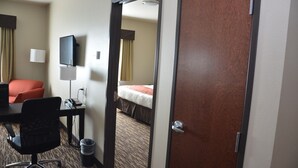 Ein Hotelzimmer mit Schreibtisch, Stuhl, Fernseher und Bett.