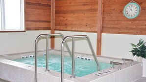 Ein Whirlpool mit Metallstufen und einer Uhr an der Wand.
