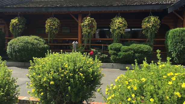 A wooden lodge with hanging flower baskets and well-maintained bushes.