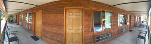 Una cabaña de troncos con techo curvo, varias ventanas y una puerta.