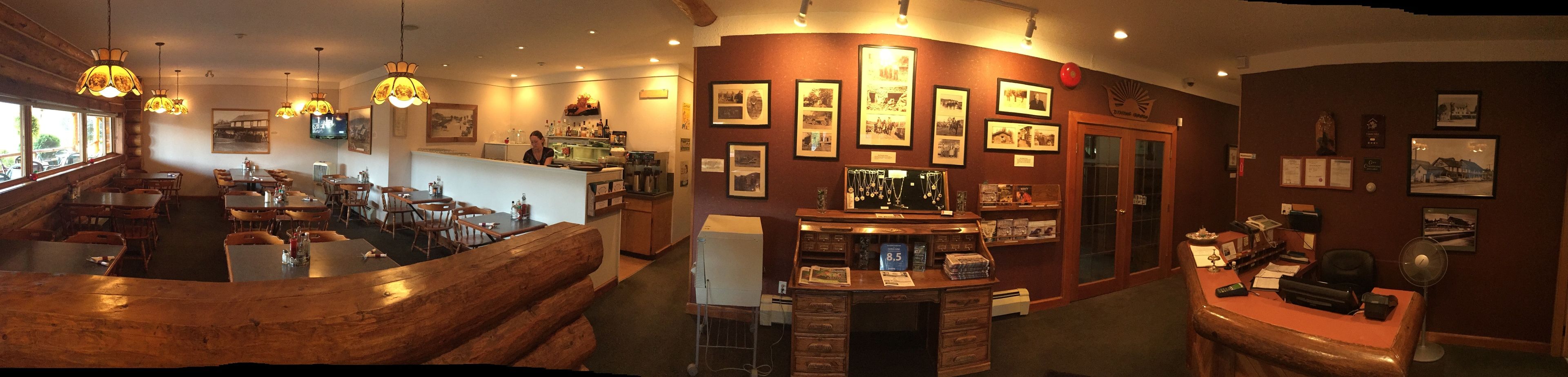 A restaurant with wooden furniture, a bar area, and various framed pictures on the walls.