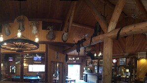 A rustic interior with wooden walls, a stone fireplace, and multiple televisions.