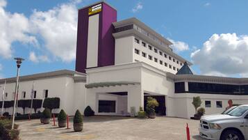 A hotel with a prominent purple and white facade, a parking lot, and a white truck parked in front.