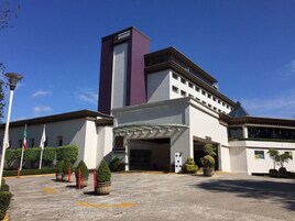Um hotel moderno com entrada imponente, área de espera coberta e exposição de bandeiras.
