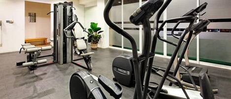 A gym with cardio machines, weight training equipment, and a bench.