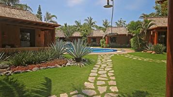 A resort with thatched-roof cottages, a swimming pool, and a stone pathway.