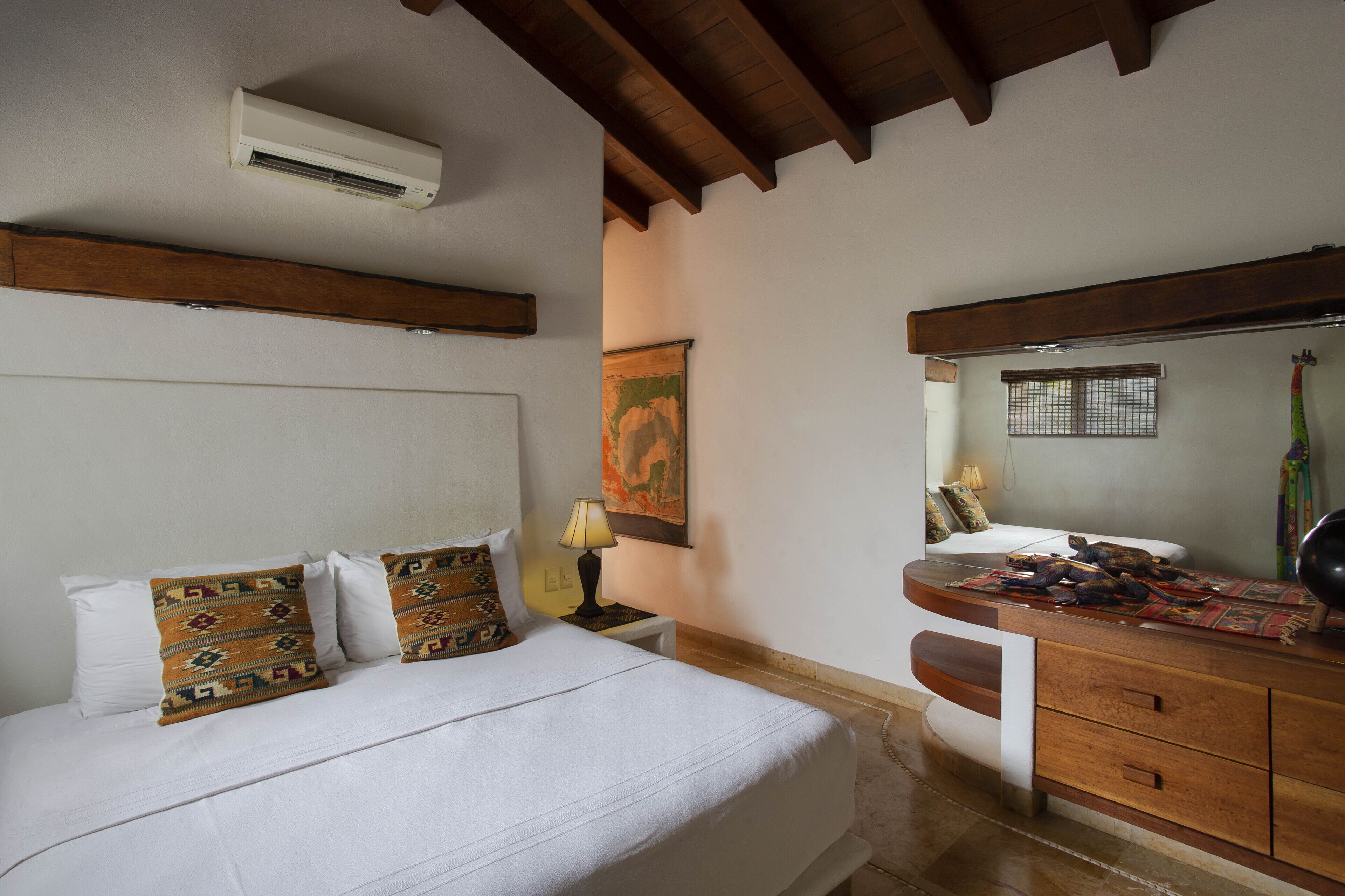 Une chambre à coucher comprenant un lit, une table de chevet, une lampe et une commode avec un miroir.