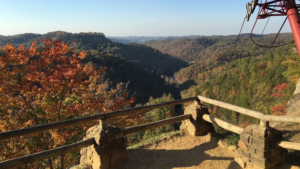 A scenic overlook with a stone retaining wall, wooden railing, and a cable car system in the background. - Black Bear Lodge Motel (Slade)