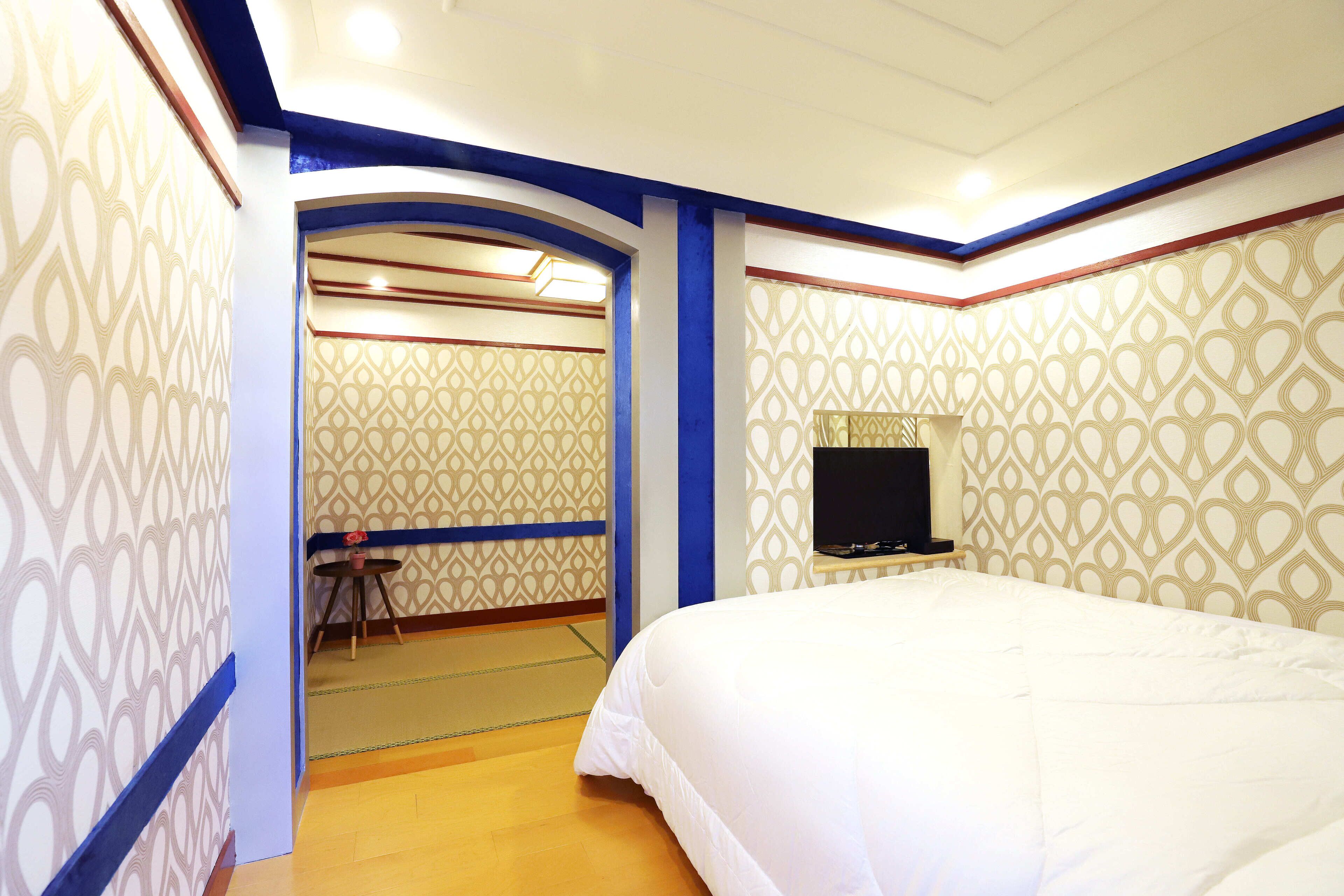 Quarto de hotel com uma cama, televisão e parede estampada.
