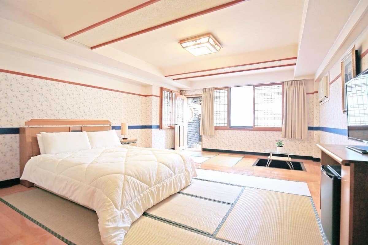 A hotel room with a bed, a desk, a window, and a bathroom.