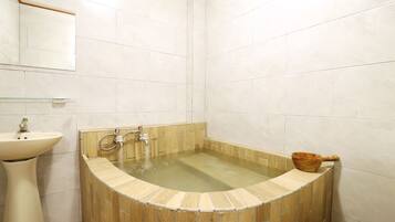 A bathroom with a freestanding bathtub, a sink, and a mirror.