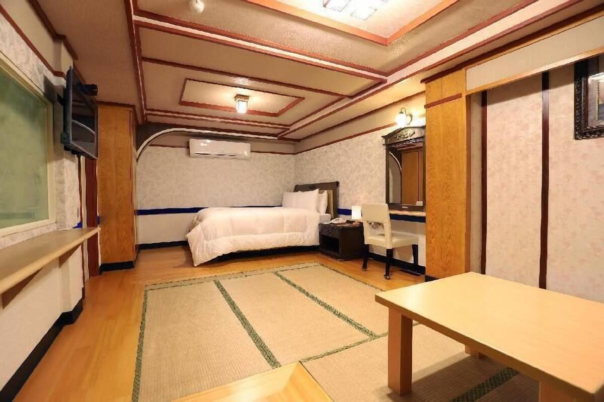 A hotel room with a bed, bedside table, chair, and a television.