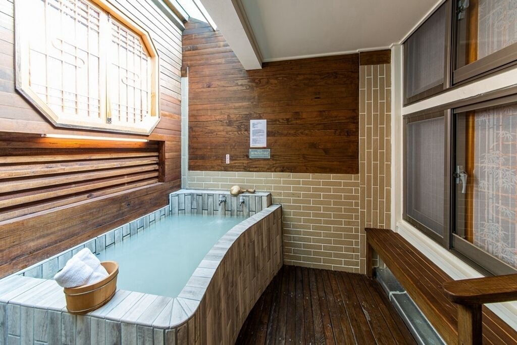 A spa area with a wooden bench, a hot tub, and a tiled floor.