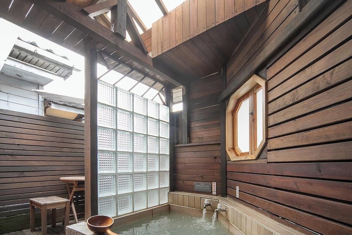 A wooden spa with a hot tub, wooden walls, and a large window.