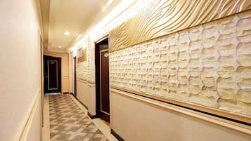 A hallway with patterned flooring, a textured wall, and a door with a number.