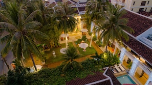 An aerial view of a hotel courtyard with palm trees, outdoor seating, and a pool. - Ha An Hotel (Hoi An)