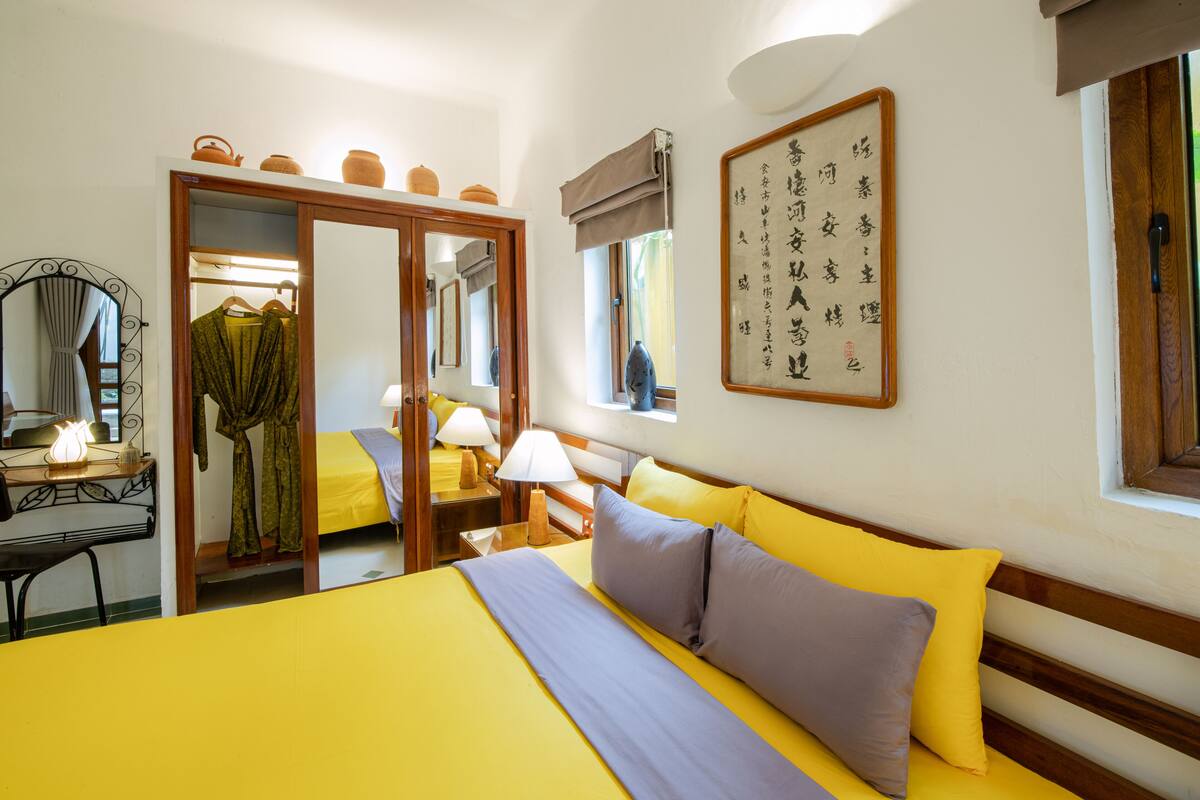 Una habitación de hotel con cama, mesita de noche, lámpara y espejo.