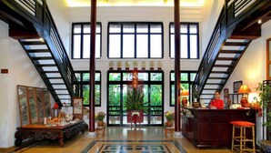 A spacious lobby with a central geometric patterned floor, a reception desk, and a staircase on either side. - Ha An Hotel (Hoi An)