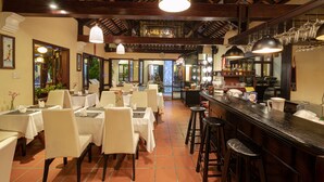 A restaurant with white tablecloths, wooden beams, and hanging pendant lights. - Ha An Hotel (Hoi An)