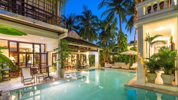 A pool area with a clear view of the pool, surrounding lounge chairs, and a dining area with tables and chairs. - Ha An Hotel (Hoi An)