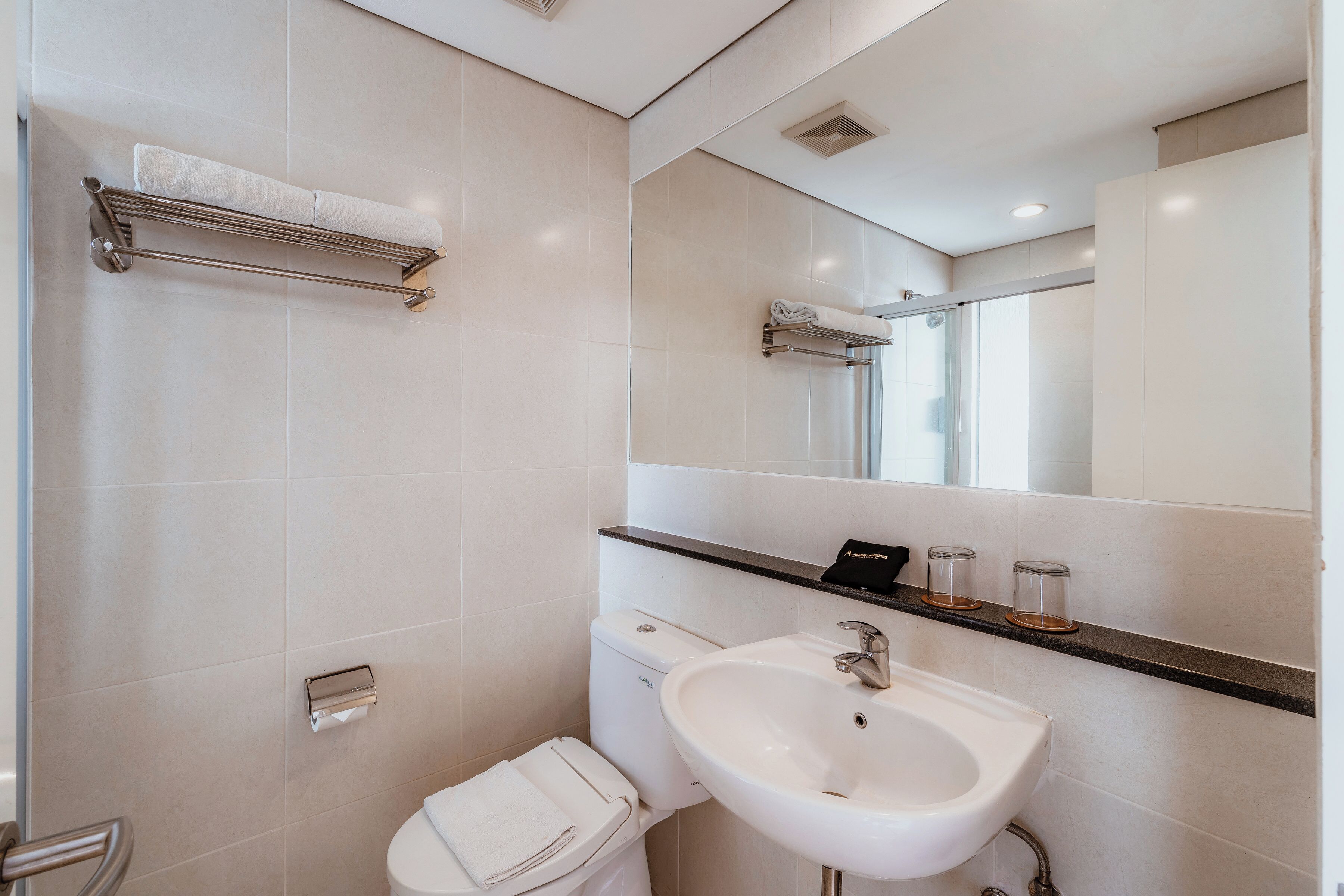 A modern bathroom with a toilet, sink, towel rack, and a mirror.