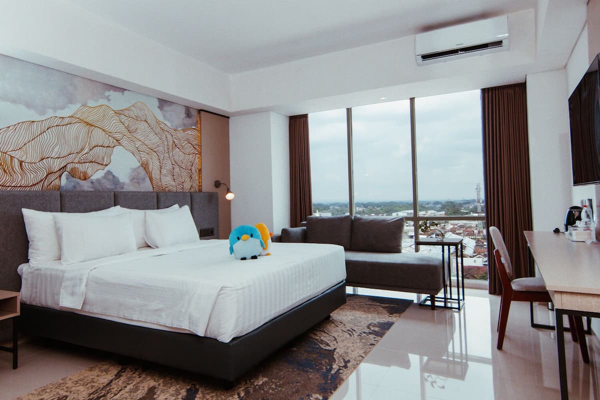 Una habitación de hotel moderna con una cama grande, un sofá, una mesa de comedor y vistas a la ciudad.